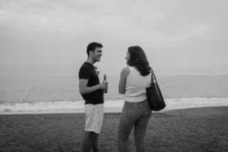 Deux personnes discutent sur une plage, l'une tenant une bouteille. Pourquoi dit-on que les chats ont 9 vies reste un mystère.