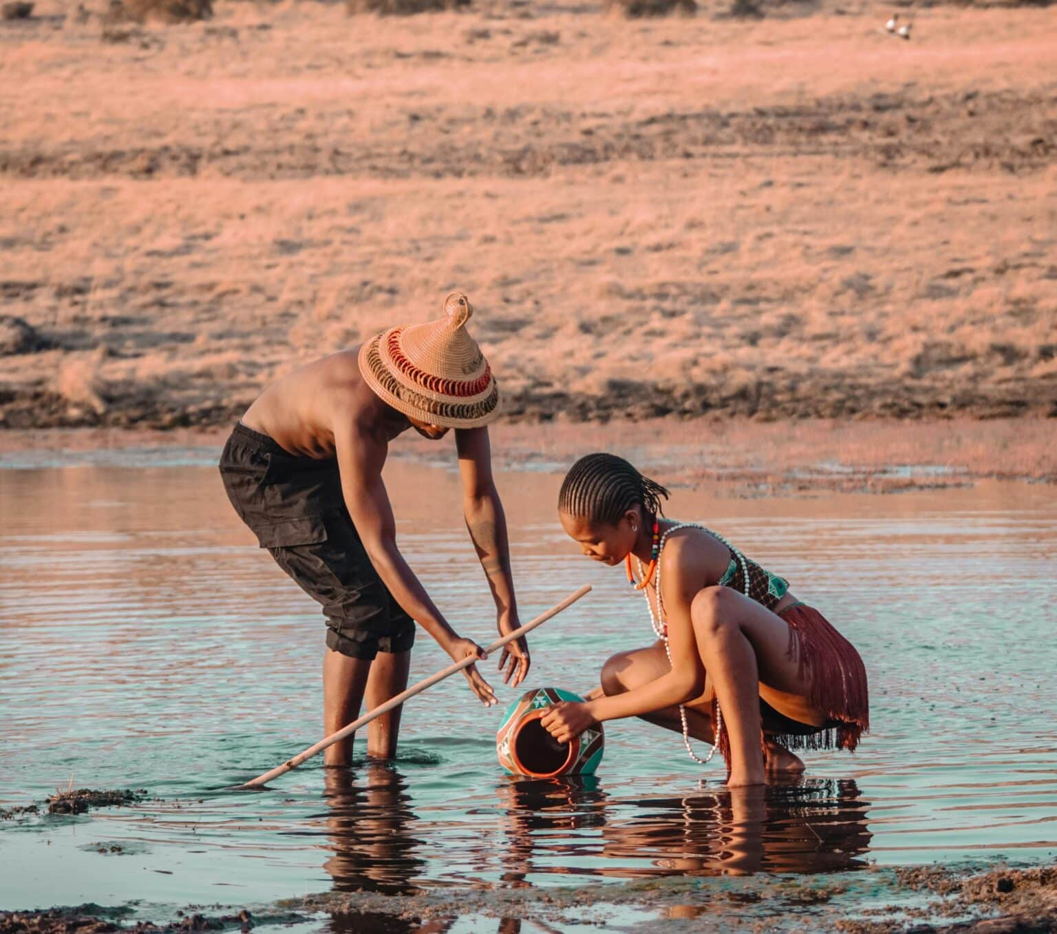 Deux personnes puisent de l'eau dans un lac peu profond, illustrant pourquoi les chats ont peur de l'eau en raison de l'humidité.