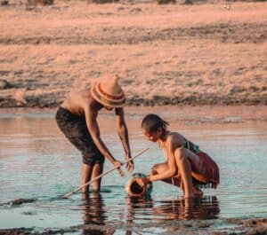 Deux personnes puisent de l'eau dans un lac peu profond, illustrant pourquoi les chats ont peur de l'eau en raison de l'humidité.