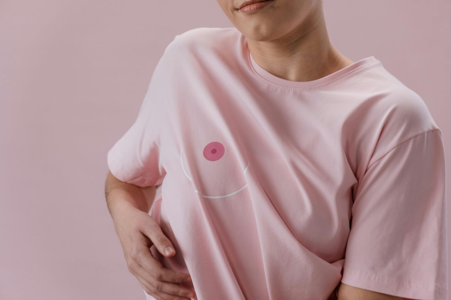 Personne en t-shirt rose avec un dessin de sein stylisé, symbolisant la lutte contre le cancer.