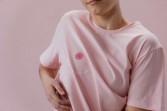 Personne en t-shirt rose avec un dessin de sein stylisé, symbolisant la lutte contre le cancer.