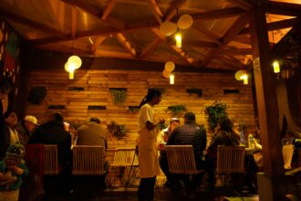 Des convives dînent dans un restaurant en bois, éclairé chaleureusement, évoquant pourquoi les chats se cachent pour mourir.